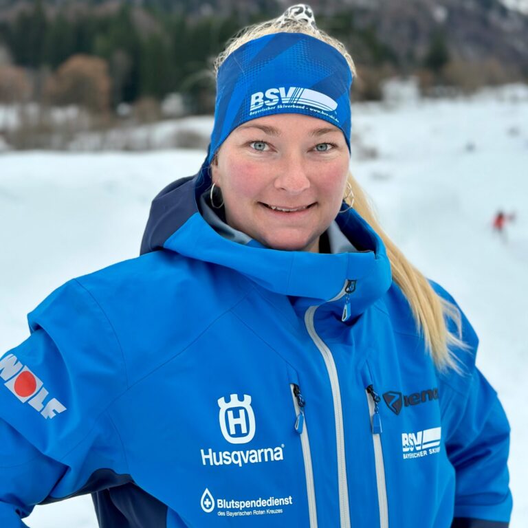 Porträtfoto einer frau in Skiklamotten und stirnband im Schnnee