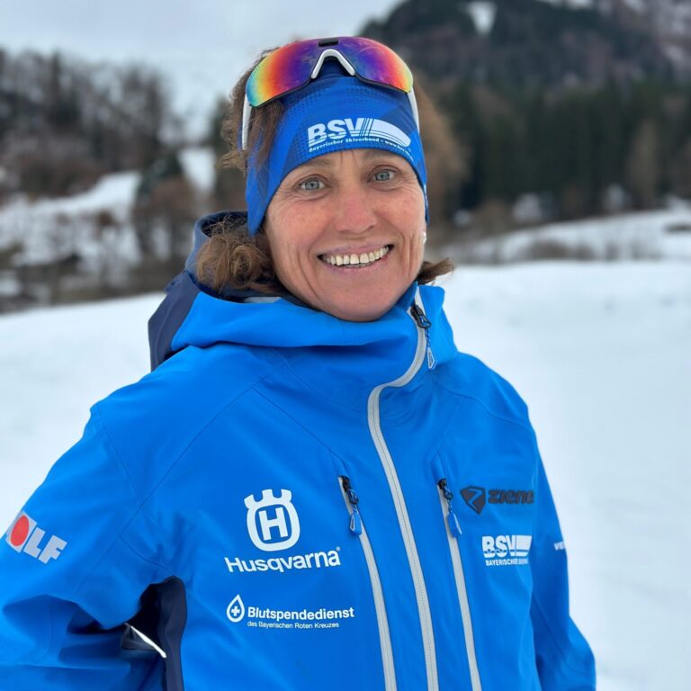 Porträtfoto einer frau in Skiklamotten und stirnband im Schnnee