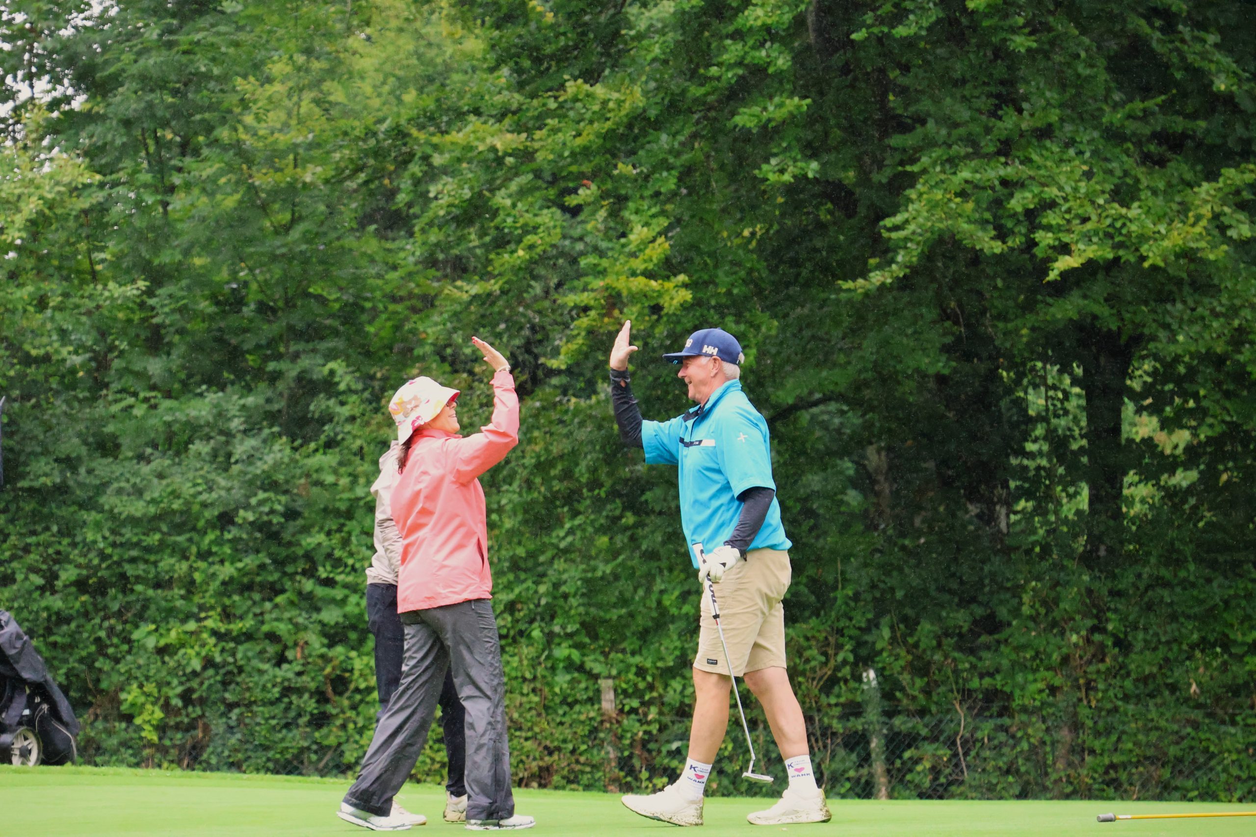 Golfspieler auf einem Golfplatz klatschen sich ab.