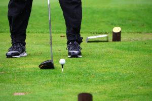 Golfschläger und Ball auf einem Tee.