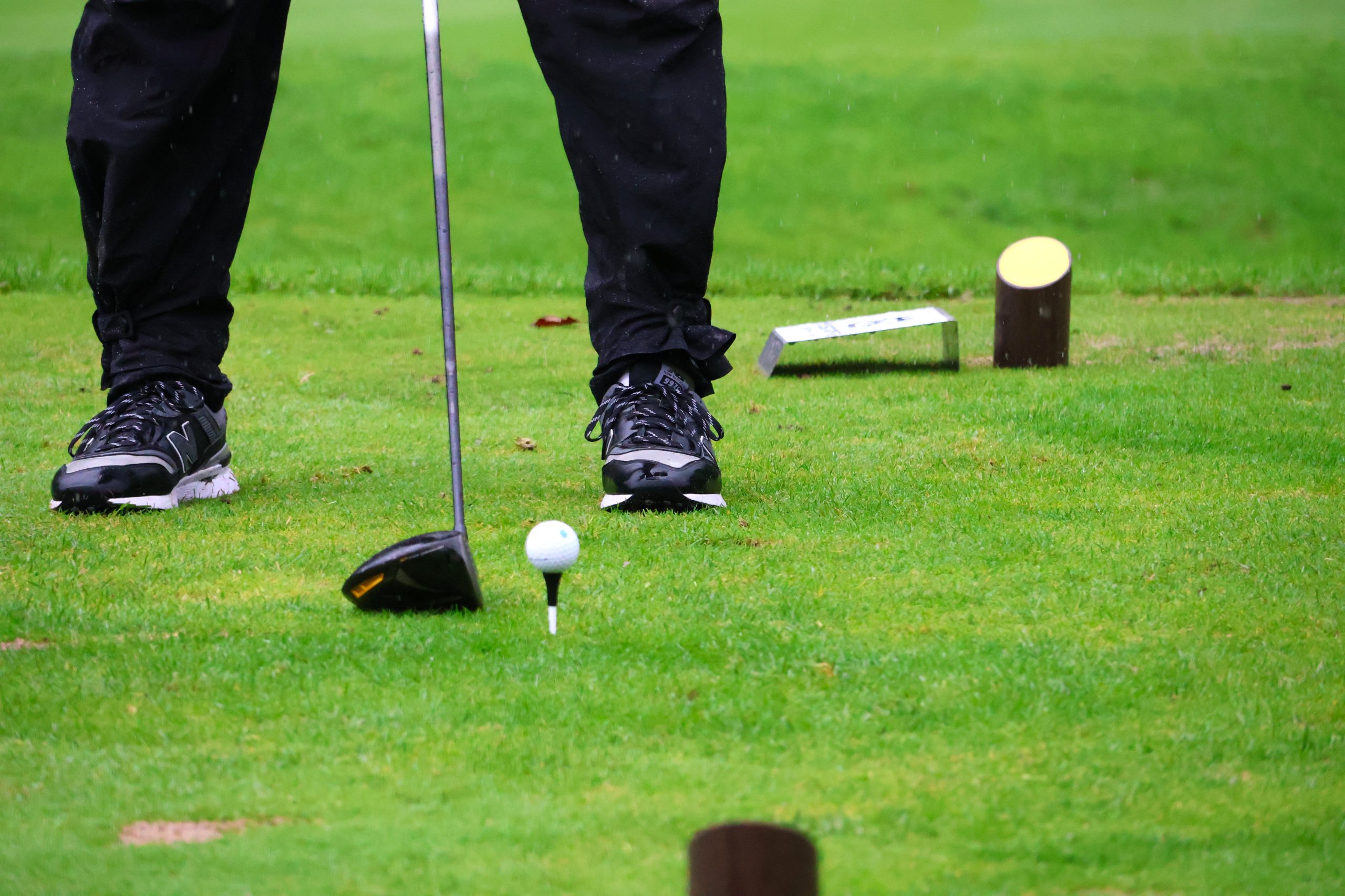Golfschläger und Ball auf einem Tee.