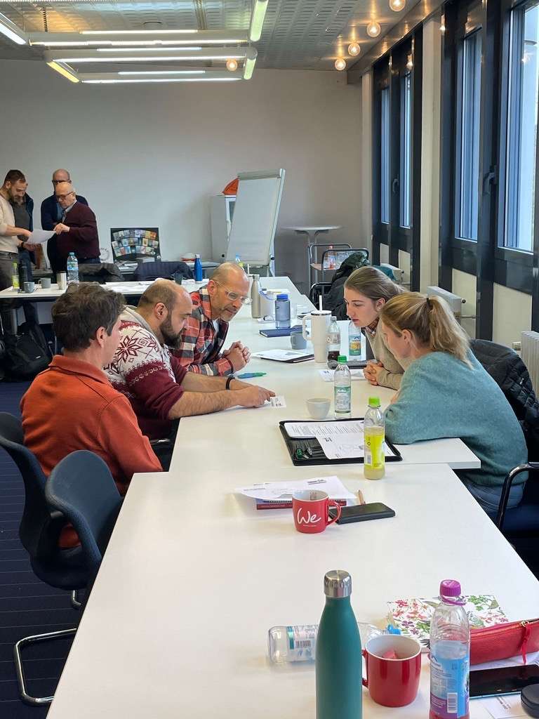 Gruppe sitzt am Tisch und bearbeitet etwas