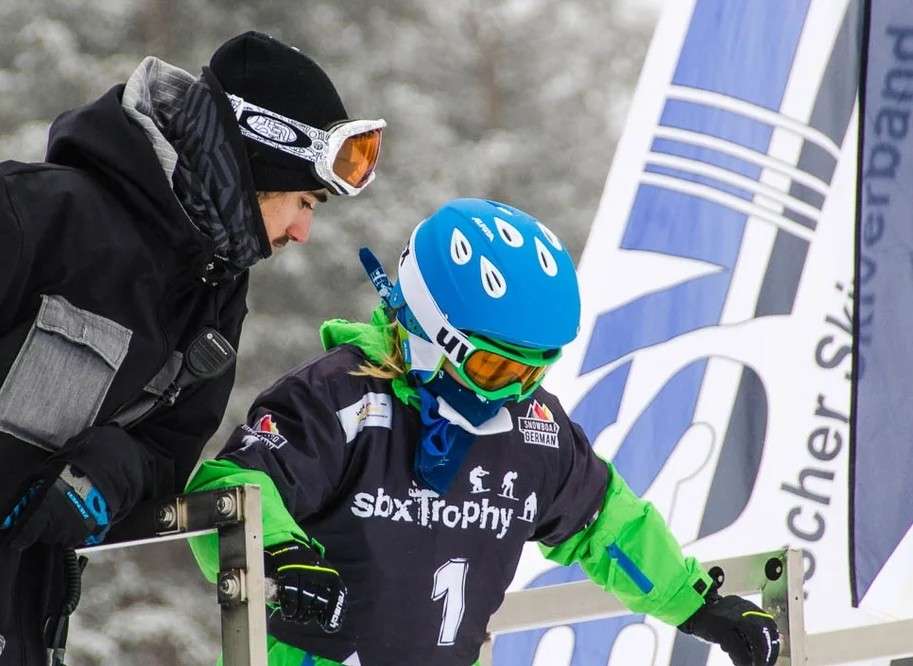 Coach und Snowboard Kind stehen am Start