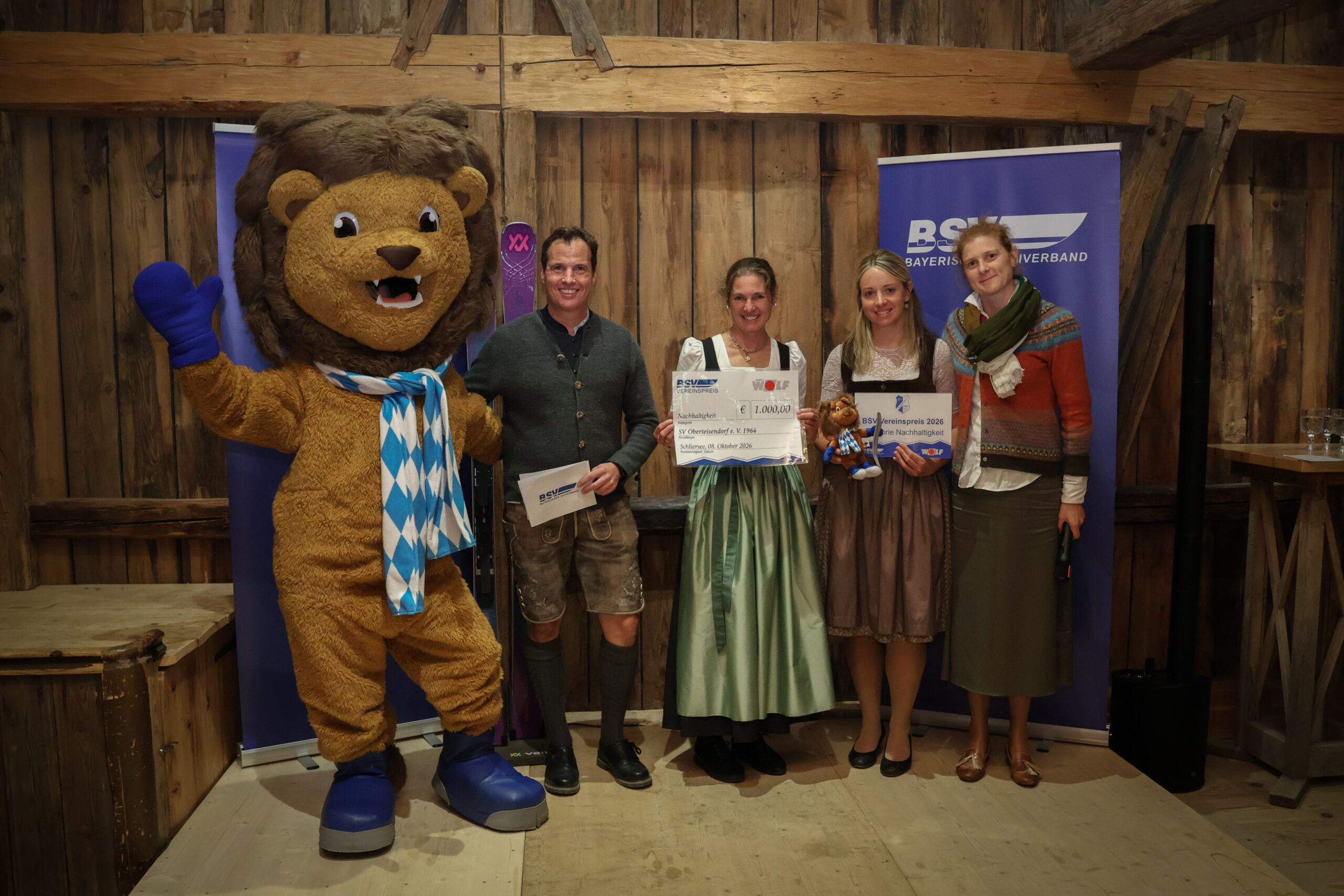 Gruppenbild mit vier Personen und einem Maskottchen bei Preisübergabe