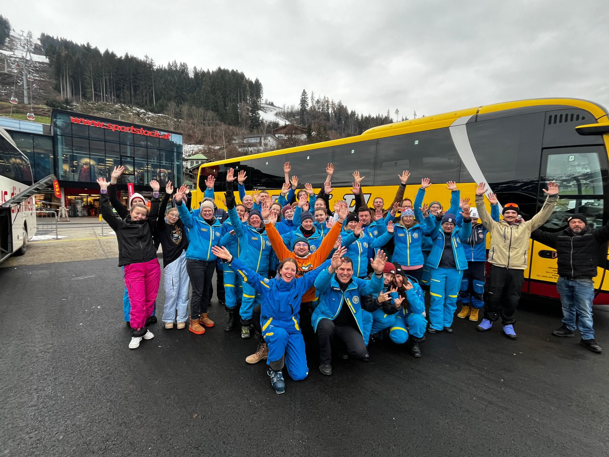 Jubelndes Gruppenbild auf dem Parkplatz vor einem Reisebus