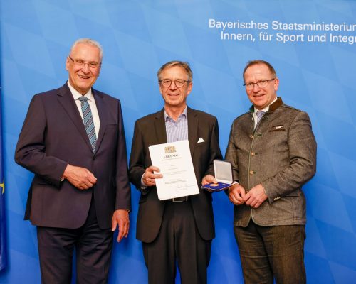 Foto von 3 Personen bei &Uuml;berreichen einer Ehrung