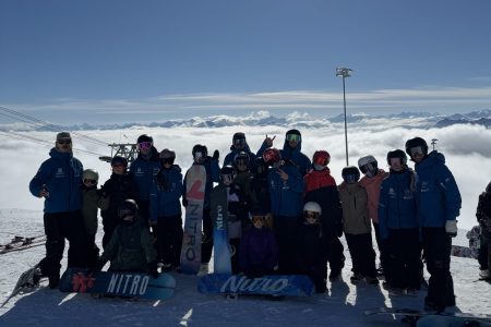 Gruppenfoto von Snowboardern über dne Wolken