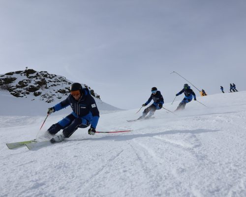 3 skifahrer fahren hintereinander auf der piste